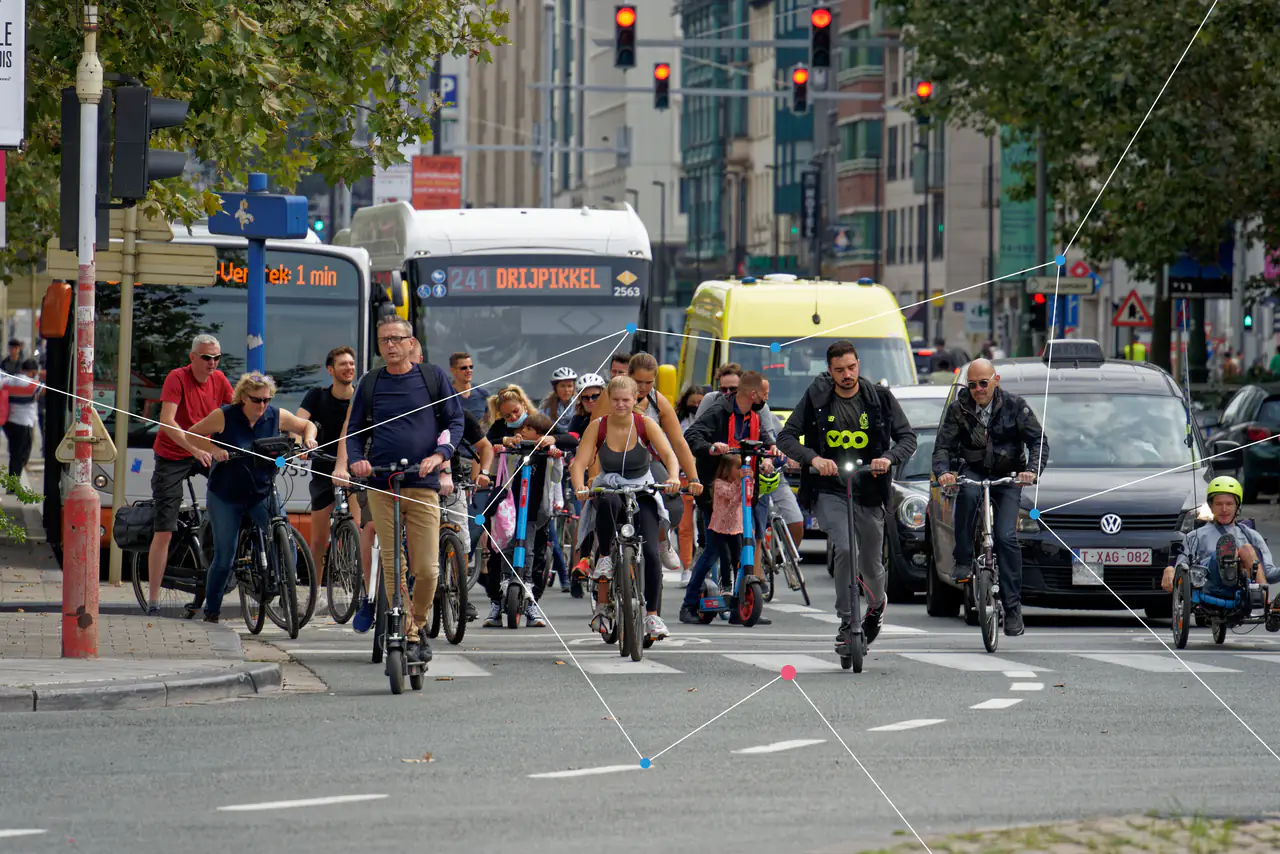 People on bicycles and scooters crossing a busy city junction.