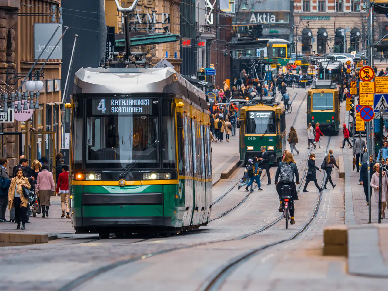 Trams and people on a busy Helsinki street.