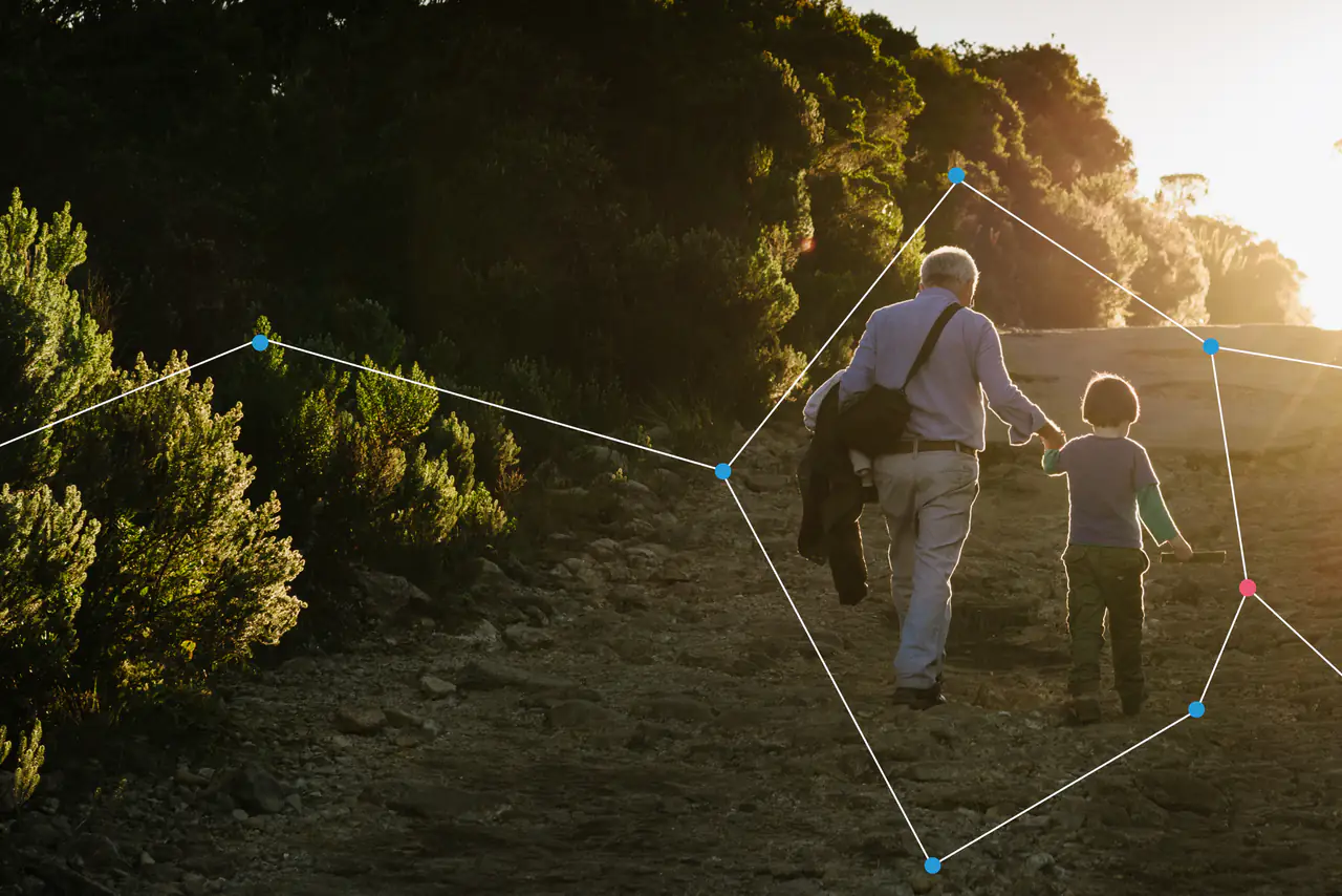 An older man and a child walking hand in hand at sunset.